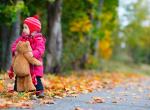 Fond ecran jeune enfant habille chaudement pompon bonnet manteau ours en peluche automne feuilles multicolores tombent image fond flou
