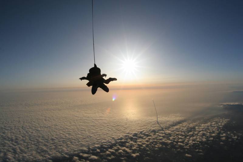 Fond ecran sport extreme parachutiste suspendu par cable chute libre au dessus nuages rayons soleil ombre image nature